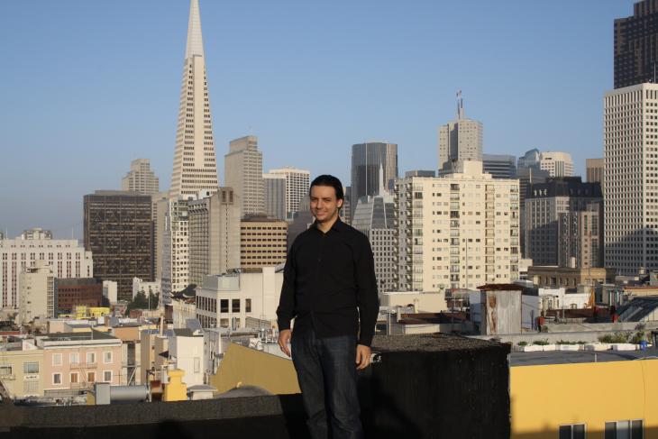 Im Vordergrund sieht man mich auf einem Häuserdach und im Hintergrund den Financial District von San Francisco.